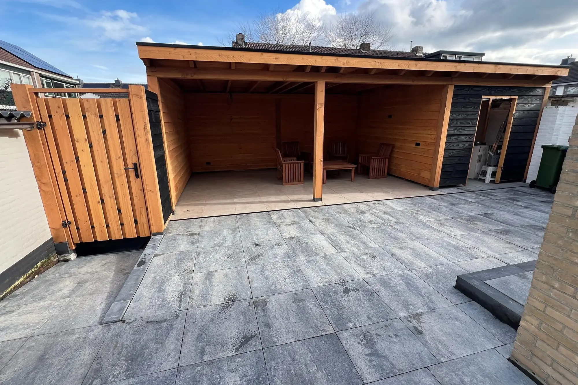 Terras van grote tegels met een houten overkapping